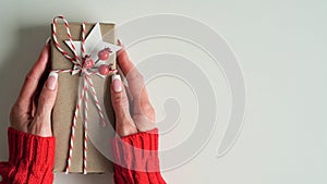 Female hands red sweater hold Christmas New Year gift box on white background,top view,flat lay,copy space. Christmas holidays