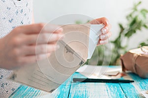 A female hands removing a postcard from the craft envelope. Close-up. The concept of a mail message and postcrossing