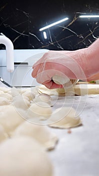 female hands roll out the dough and shape the meat pies in the kitchen