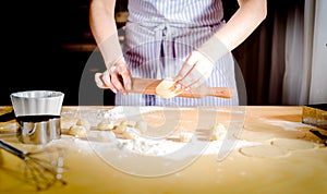 Female hands rolling out dough on kitchen table, close up