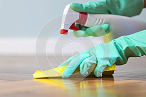 Female hands with rubber gloves cleaning parquet