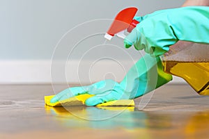 Female hands with rubber gloves cleaning parquet