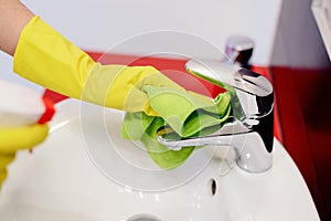 Female hands with rubber protective gloves cleaning tap