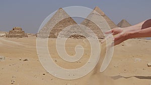 Female hands is with a sand and the Great Pyramids of Giza in Egypt.