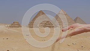 Female hands is with a sand and the Great Pyramids of Giza in Egypt.
