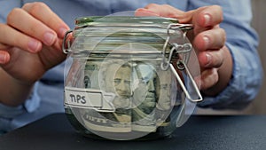 Female hands Saving Money turn Glass Jar filled with Dollars banknotes. TIPS transcription in front of jar. Managing