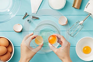 Female hands separate egg white from yolk for whipped cream.