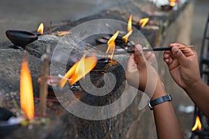 Female hands set fire to fragrant sticks in the temple offerings