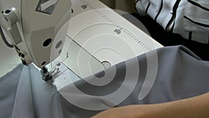 Female hands sew a gray fabric on a sewing machine