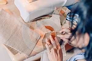 Female hands sewing fabric with needle at seamstress workplace of sewing process.