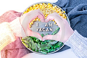 Female hands in shape of heart love I AM VEGAN text in plate. Veganism, vegetarian healthy lifestyle. Healthy eating