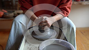 Female hands shaping clay pot working on pottery wheel