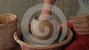 Female hands shaping clay vase on pottery wheel