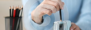 Female hands sharping pencil with electronic sharpener closeup