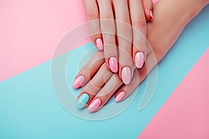 Female hands showcasing pastel stylish trendy manicure against a duotone blue and pink background