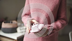 Female hands showing knitted baby booties. Knitted shoes handmade for baby