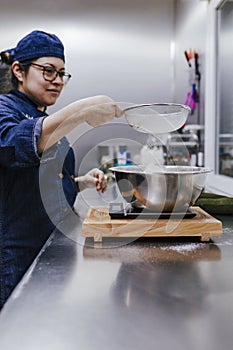 Female hands sifting flour by sieve in bowl for recipe. bakery concept