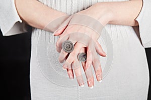 Female hands with signet rings on fingers over photo