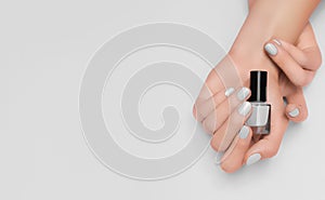 Female hands with silver nail design. Gray nail polish manicure. Woman hands hold silver varnish bottle