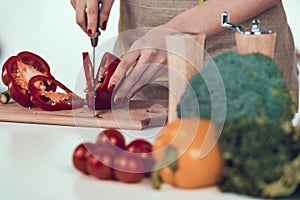 Female Hands Slicing Bell Pepper on Wooden Board.