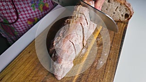 female hands slicing bread on a cutting board, close-up, slow motion