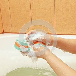 Female hands soaping green sponge with soap