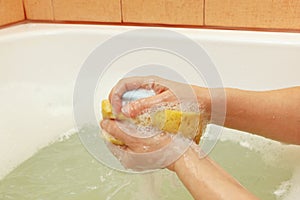 Female hands soaping yellow sponge with soap