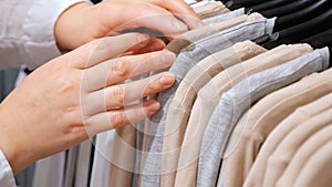 Female hands sort cotton pullovers on a hanger in a clothing store.