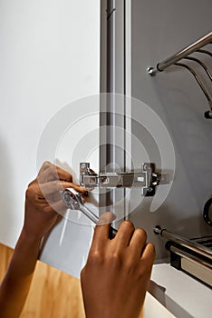 Female hands with spanner, fixing cupboard door