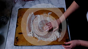 Female hands sprinkle flour on a pie board