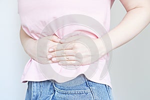 Female hands squeeze the stomach on white background, the concept of abdominal pain.