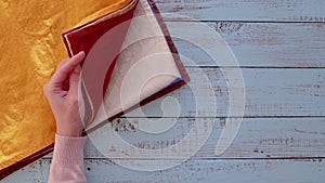 Female hands stack linen napkins of different colors on a wooden old table.