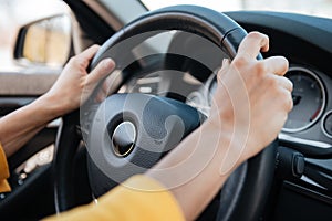 Female hands on steering wheel while driving a car