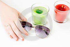 Female hands with sun glasses, candles and nail art