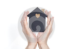 Female hands surround a model of a dark house on a light background. Real estate and insurance concept. Protecting your family at