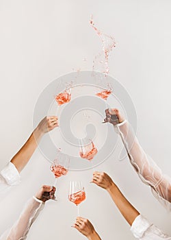 Female hands swirling glasses of rose wine making splashes