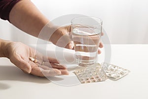 Female hands take pills and a glass of water, blister pack on th