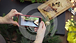 female hands taking photo christmas decorations table using smartphone camera