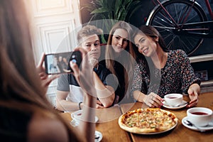 Female hands taking photo with smartphone of young cheerful friends