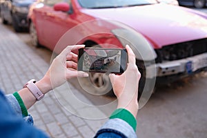 Female hands taking pictures of car damage on mobile phone closeup