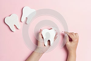 Female hands with tooth symbol and toothbrush on pink background. Dental health, brushing and whitening teeth concept