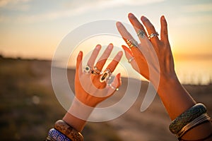 Female hands touch the sun. Hippie woman hands with silver rings at sunset. Indie boho vibes and bohemian style
