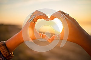 Female hands touch the sun. Hippie woman hands with silver rings at sunset. Indie boho vibes and bohemian style