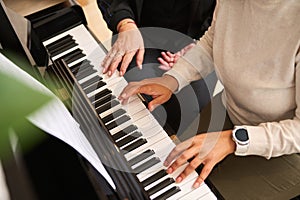 Female hands touching white and black piano keys while performing a musical composition, playing grand piano indoor