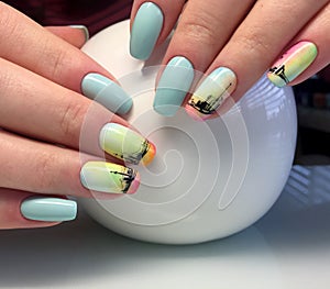 Female hands with a turquoise manicure and a painted ship. interesting and fashionable design