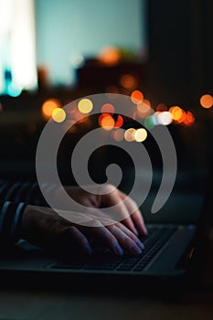 Female hands typing laptop computer keyboard in the dark