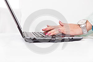 Female hands typing on laptop keyboard with red nail polish