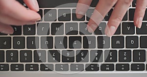 Female hands typing on laptop keyboard. Top view, close-up