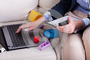 Female hands typing on laptop and kids toys