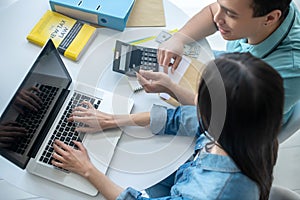 Female hands typing on laptop, male hands holding credit card